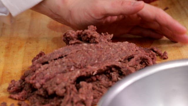 Hand preparing ground beef meat on a cutting board