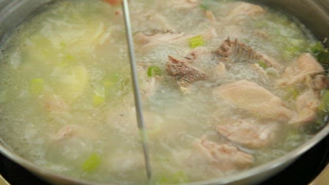 Picking up a piece of chicken using chopsticks