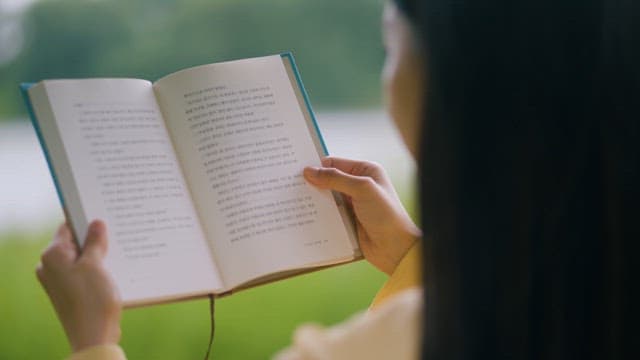 Person reading a book outdoors