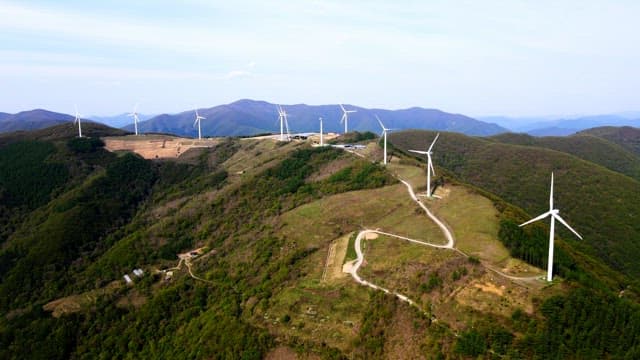 Wind turbines lined up along a mountain ridge on a sunny day
