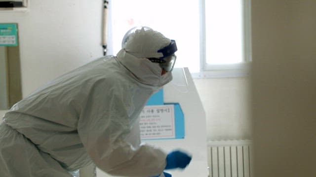 Healthcare worker in protective clothing performing a task in a hospital room