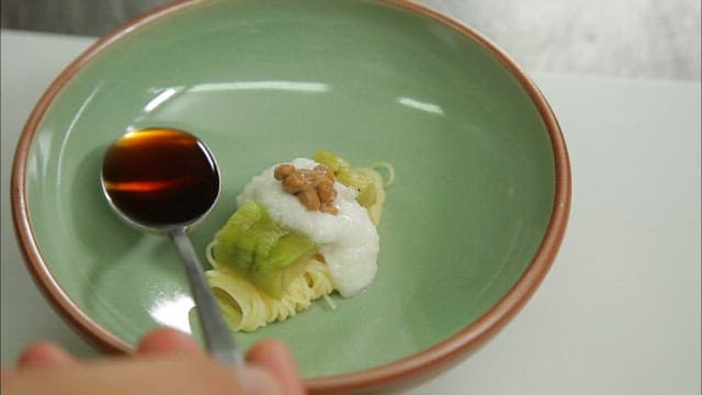 Adding soy sauce to buckwheat soba with natto and grilled eggplant