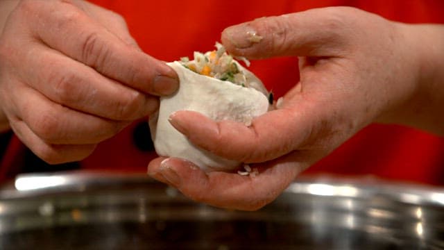 Hands making dumplings with filling