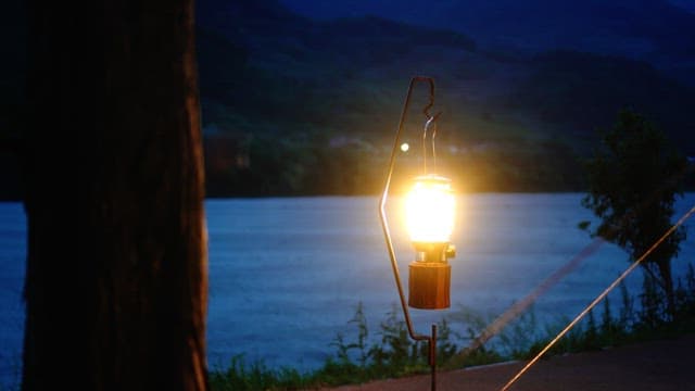 Lantern lit by a riverside at dusk