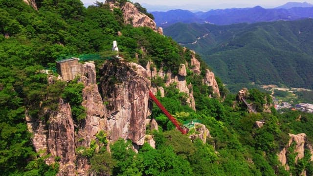 Tourists climbing the red steps in a mountain covered with lush green trees
