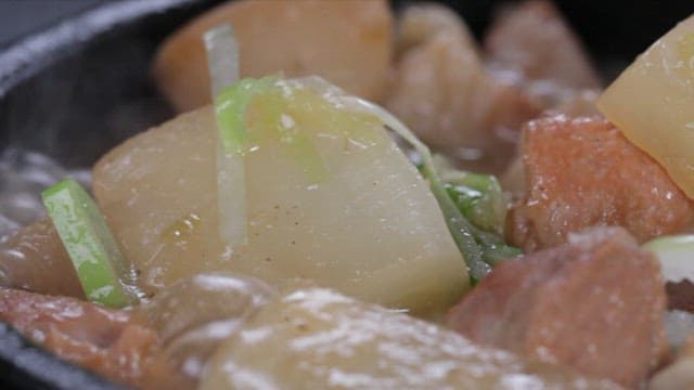 Spoonful of pork and radish soup boiling in a pot