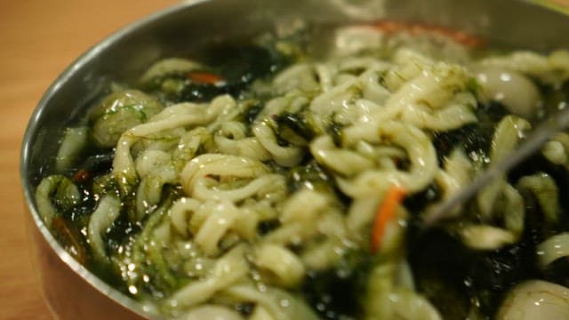 Fresh kalguksu noodles with seaweed fulvescens picked up with chopsticks