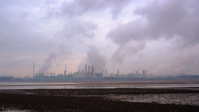 Industrial factory in the distance under a cloudy sky near a wetland