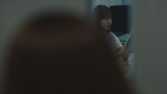 Woman reading a book in a classroom beyond the window