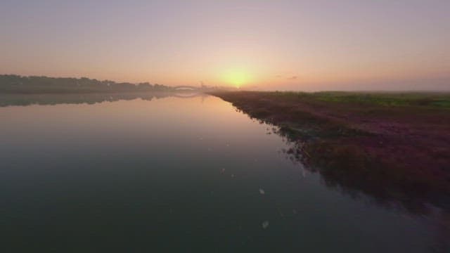 Serene river at sunrise with a bridge