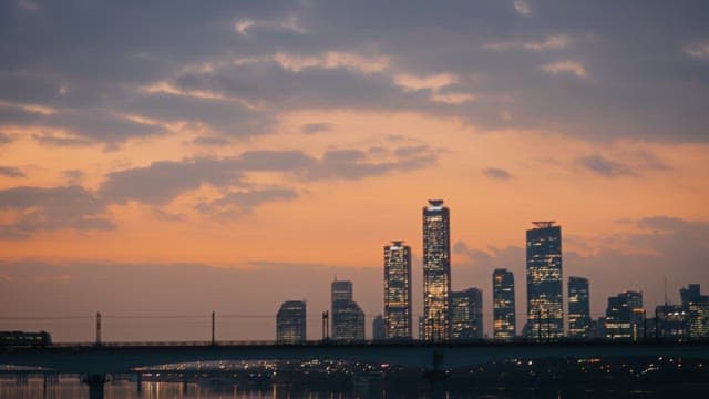 City skyline at sunset with bridge with subway passing by