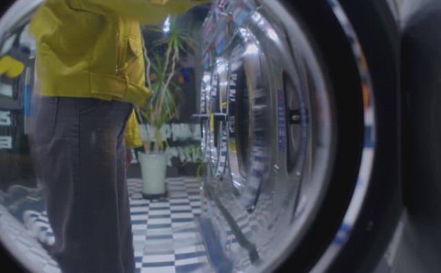 Woman examining washing machine at coin laundromat