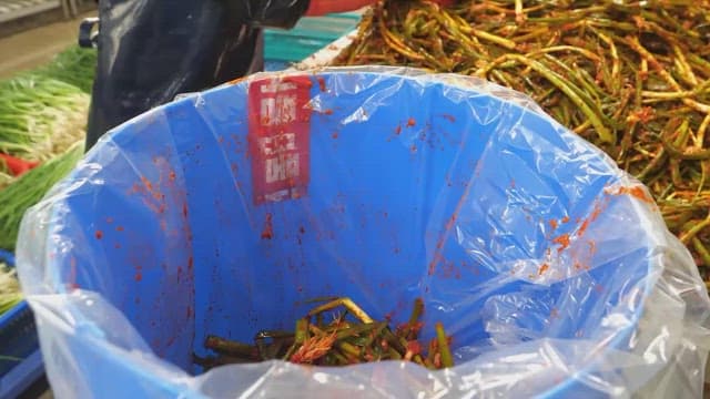 Person preparing and packaging traditional green onion kimchi