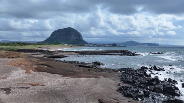 Cloudy seaside with distant mountains visible under a cloudy sky