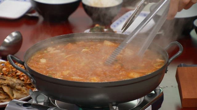 Cutting meat in kimchi stew with scissors in a pot