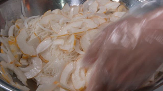 Mixing Fresh Korean Melons and Noodles in a Metal Bowl