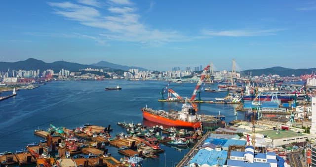 Bustling port city during the day with cargo ships and cranes
