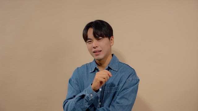 Man in denim shirt wagging his finger and laughing