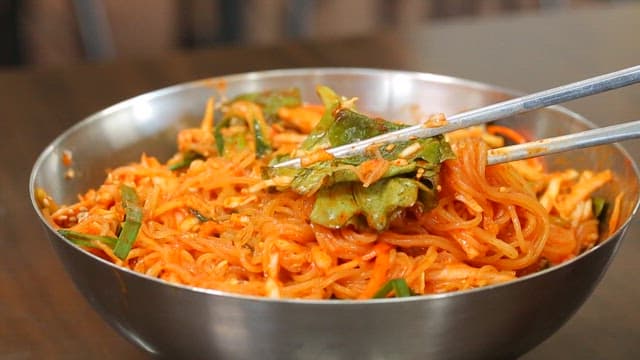 Chopstickful of delicious bibim jjolmyeon with fresh vegetables