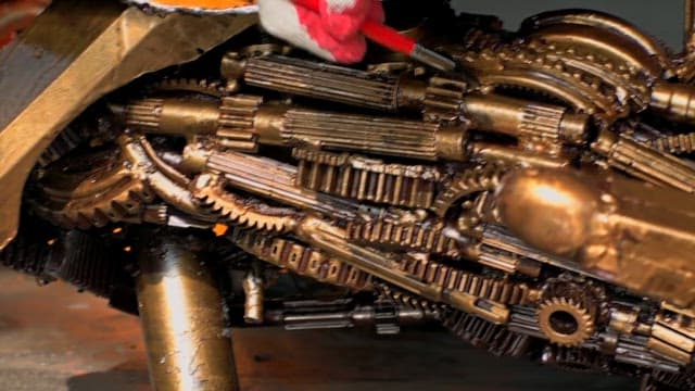 Gloved hands painting miniature metal machine parts