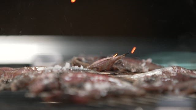 Salt sprinkled on anchovies being cooked on the grill