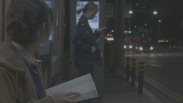 Passengers waiting for bus at the bus stop at night in city