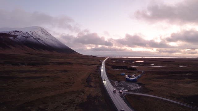 Winding road by a snowy mountain at dusk