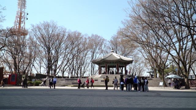 People walking through a park with a traditional Korean pavilion
