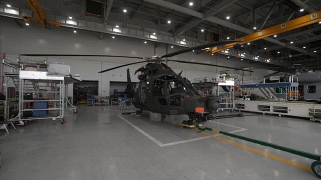 Black helicopter inside an indoor hangar with bright lights