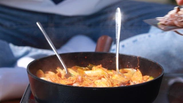 Adding webfoot octopus to the frying pan where the spicy tteokbokki is being cooked
