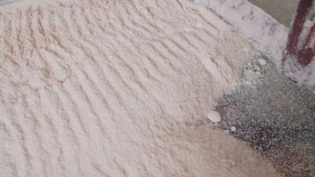 Sugarcane being processed into sugar and transported by machinery in a factory