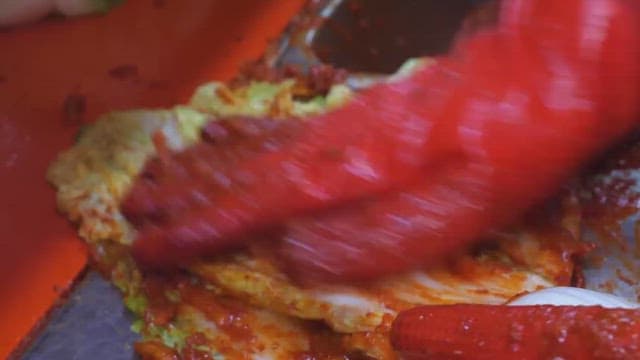 Making kimchi by adding chili pepper seasoning to cabbage