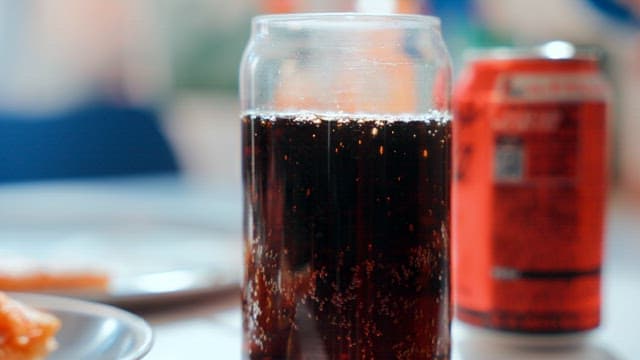 Glass of cola with bubbles on a table
