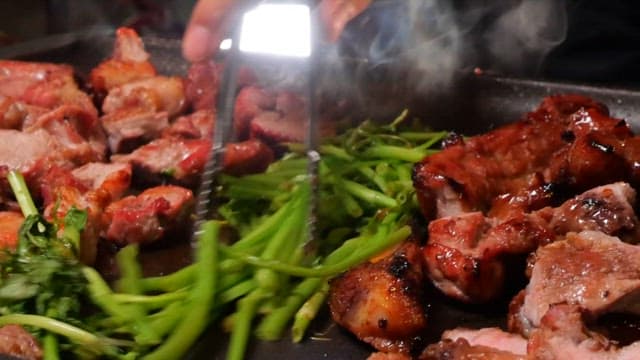 Grilling meat with greens on a hot plate