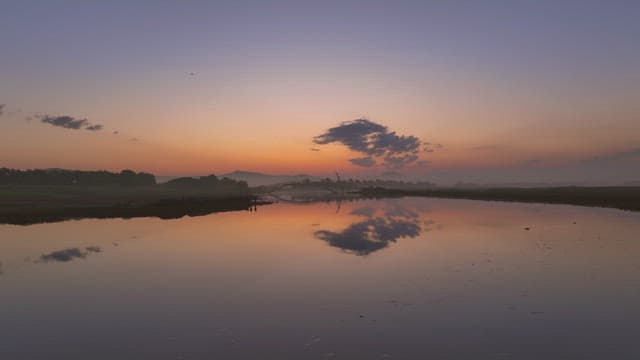 Serene river at sunset with a bridge