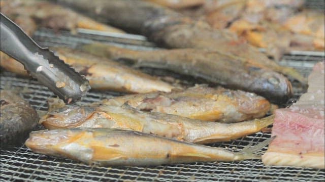Crispy grilled yellow croaker on an outdoor grill