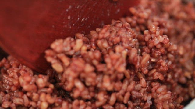 Stirring cooked brown rice with a wooden spatula