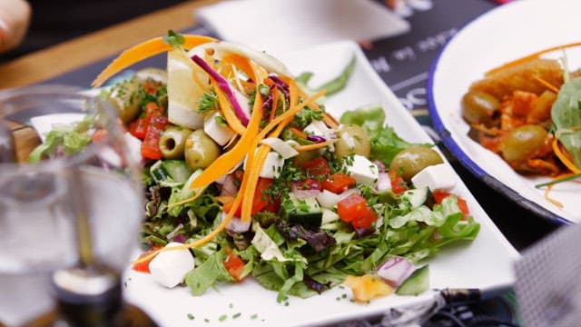 Appetizing dishes set on a dining table with fresh vegetable salad