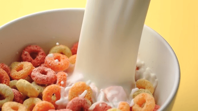 Pouring milk into cereal in a white bowl