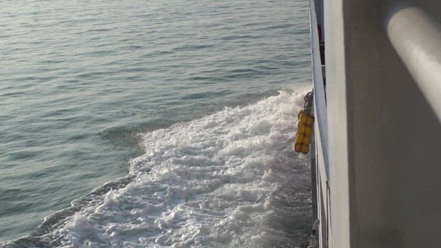 Ferry for transporting vehicles moving through the sea with islands in the distance