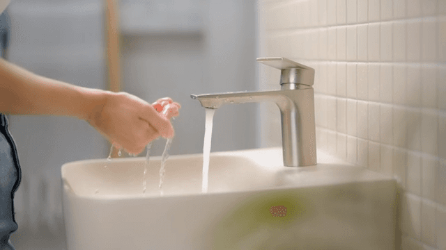 Person washing hands at a sink in a clean bathroom