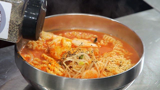 Sprinkling pepper on ramen with bean sprouts and rice cakes