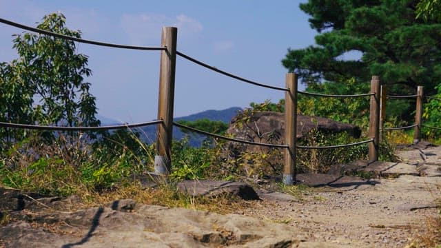 Wooden railing along a mountain path in a sunny afternoon.
