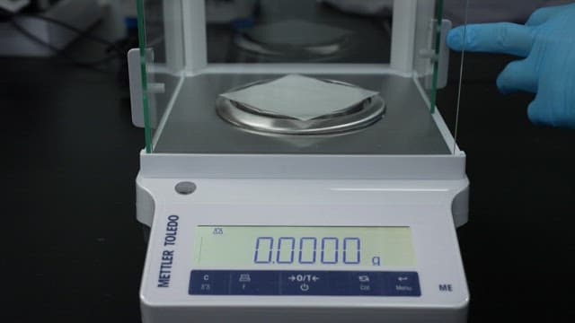 Scientist weighing a coin on a precise digital scale
