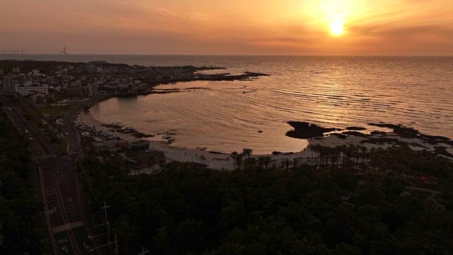 Sunset over a calm ocean with a coastal village