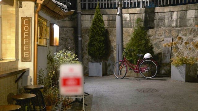 Night view of a quiet corner with a bicycle beside a coffee shop.