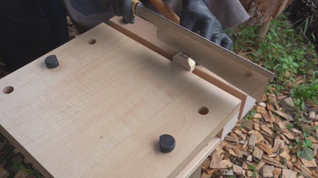 Person carving wood with a saw outdoors