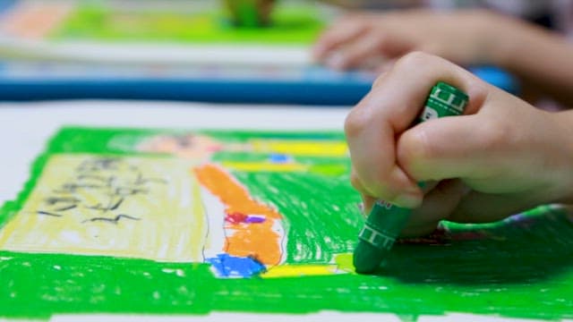 Children Coloring Pictures with Crayons