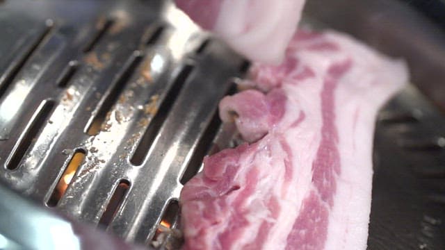 Raw pork belly on a metal grill