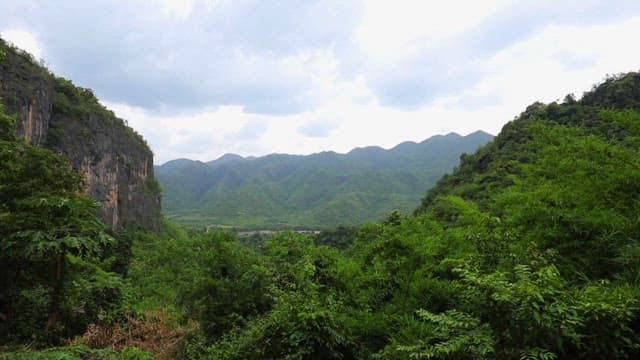 Lush Green Mountain Range Under Cloudy Skies